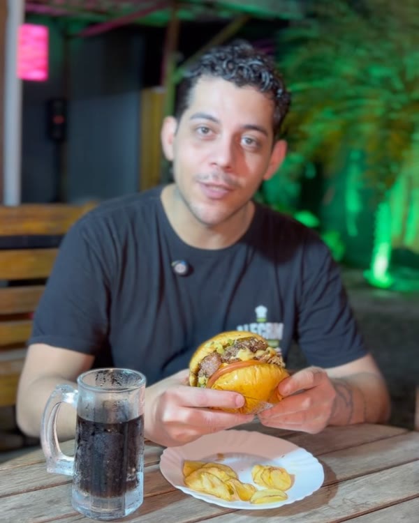 Cliente com hambúrguer na mesa do jardim